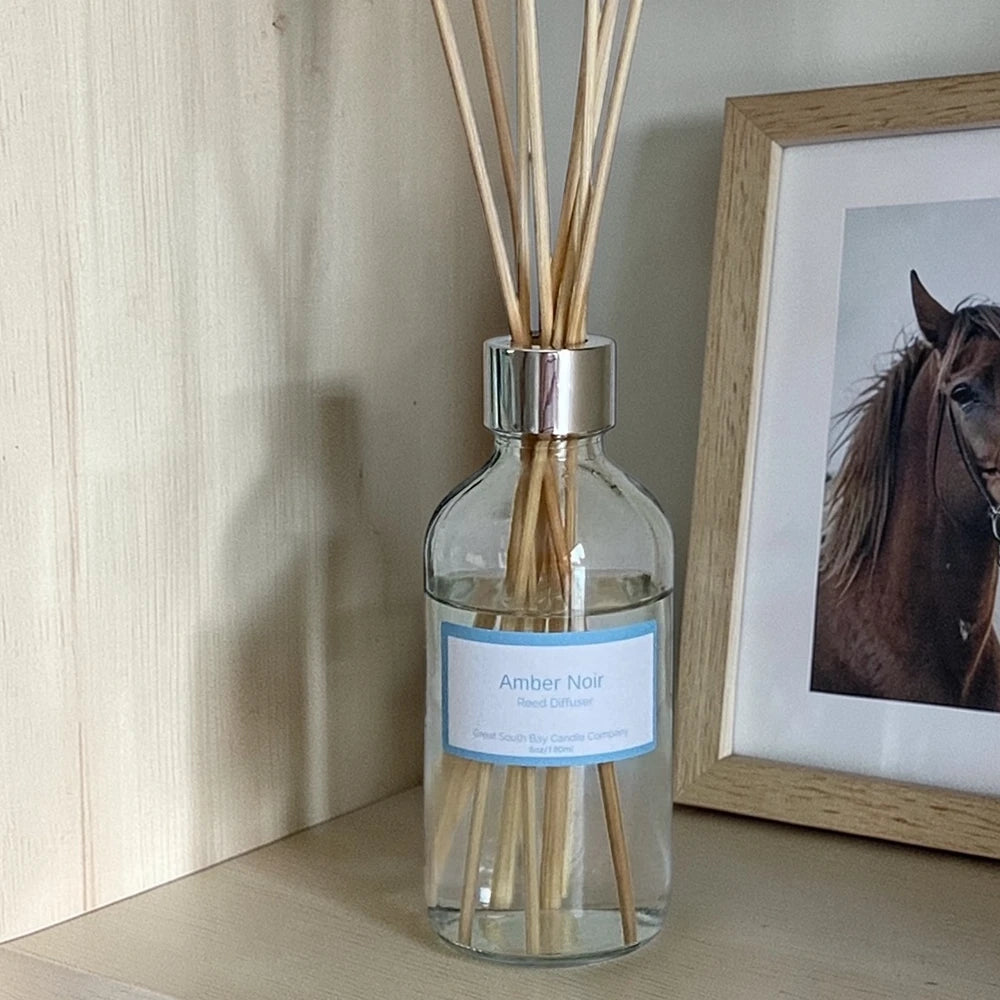 Amber Noir reed diffuser on a bookshelf with a picture of a horse.