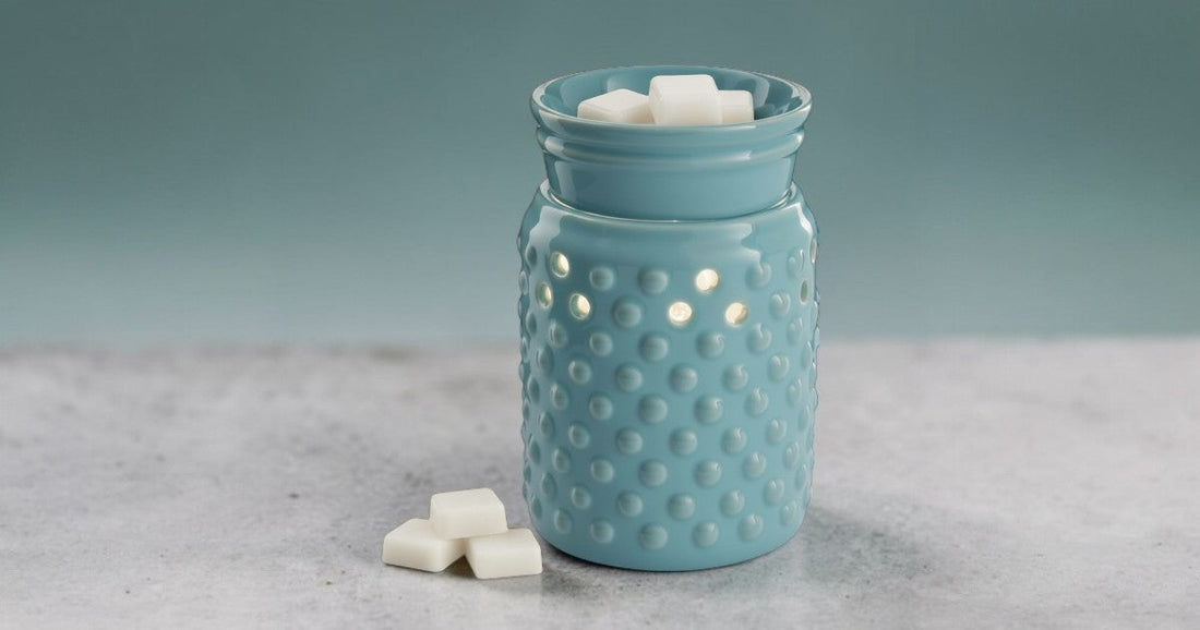 Blue hobnail candle wax warmer on a gray surface with a light blue background.