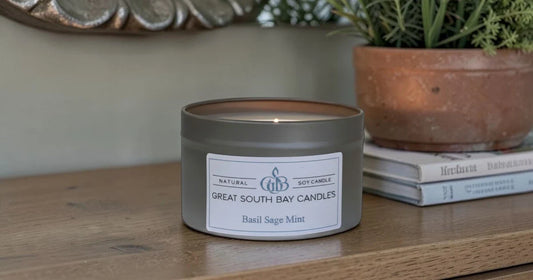 Basil sage mint candle on a wooden table with books and plant.