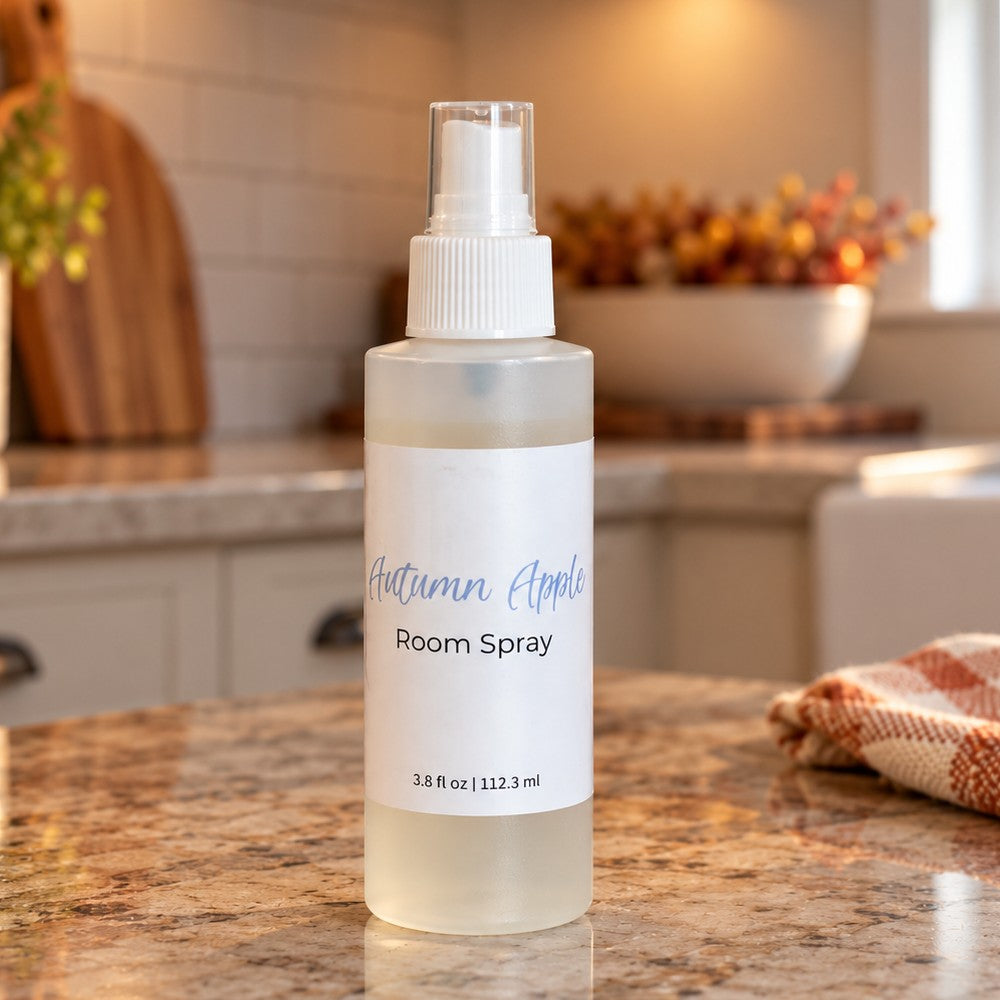 A bottle of Autumn Apple room spray on a granite countertop in a kitchen setting. The clear plastic bottle has a white spray cap and labeled Autumn Apple Room Spray.