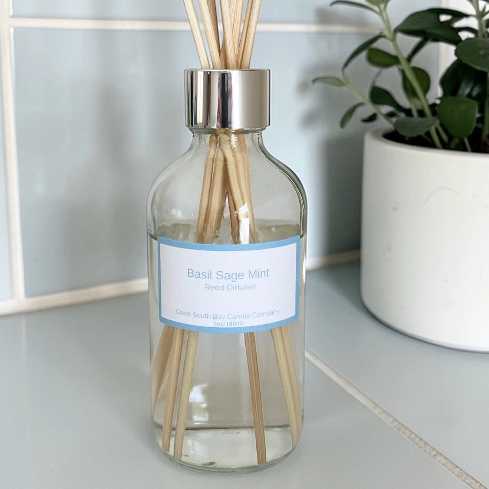 Basil Sage Mint reed diffuser on a bathroom countertop.