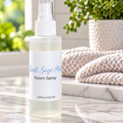 A basil sage mint room spray bottom on a kitchen counter with a plant and hand towels.