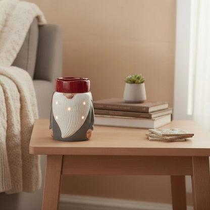 Decorative gnome wax warmer on a wooden table with books and a plant in the background.