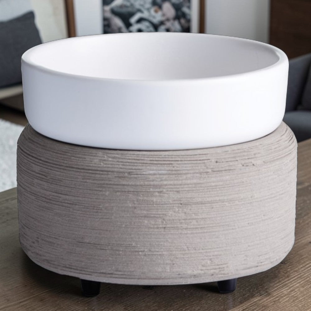 Grey textured candle warmer with a white top dish on a wooden table.