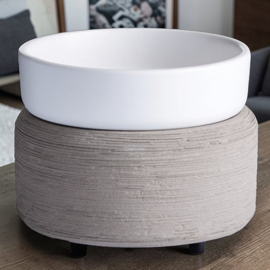 Grey textured candle warmer with a white top dish on a wooden table.