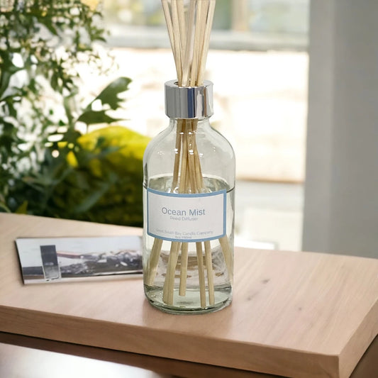 Ocean Mist reed diffuser with rattan reeds on a wooden table.