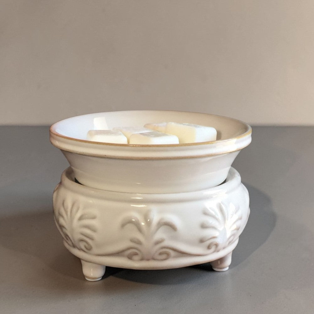 Beige ceramic wax warmer on a gray surface.