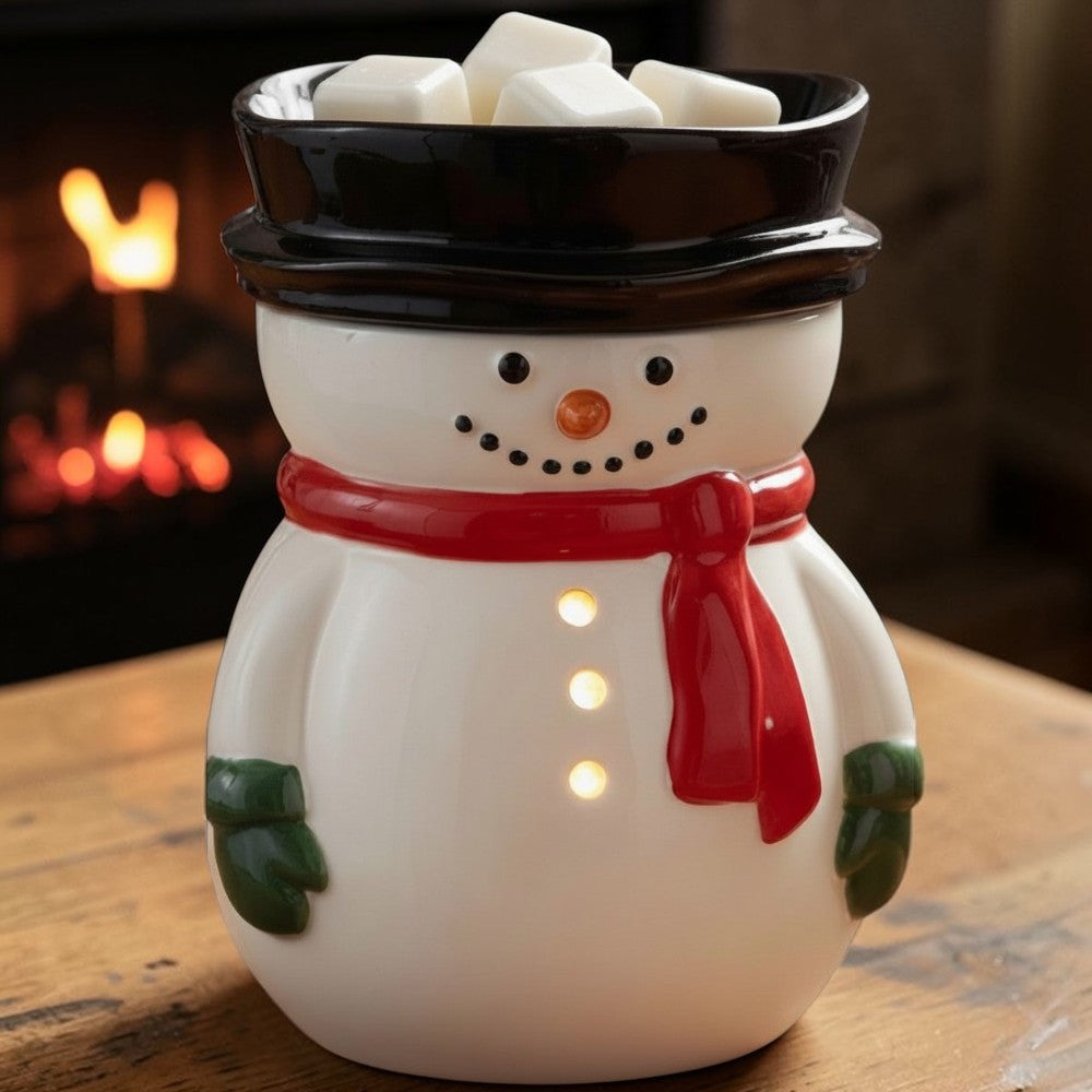 Snowman wax fragrance warmer on a table with a fireplace in the background.
