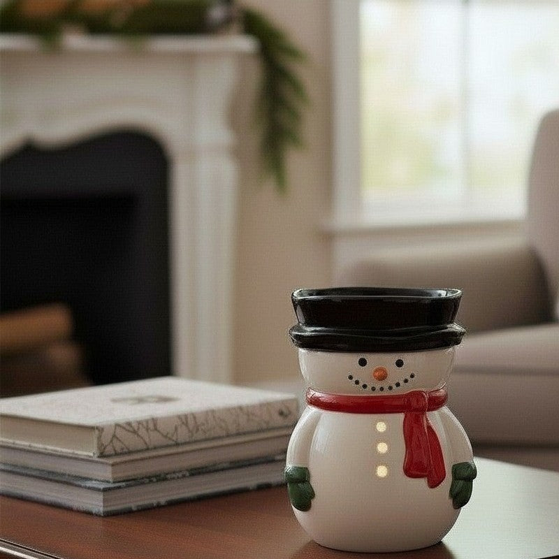 Snowman candle warmer on a table with a fireplace and window in the background.