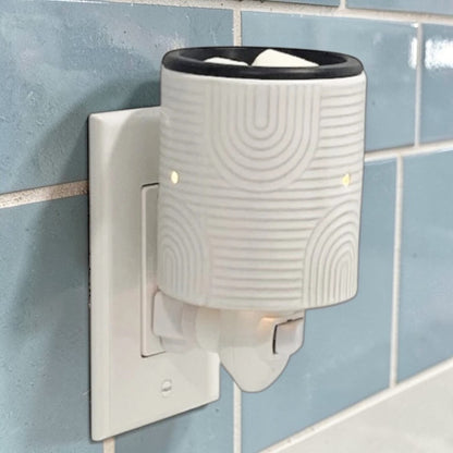 Art Deco candle wax warmer plugged into an outlet on the wall.