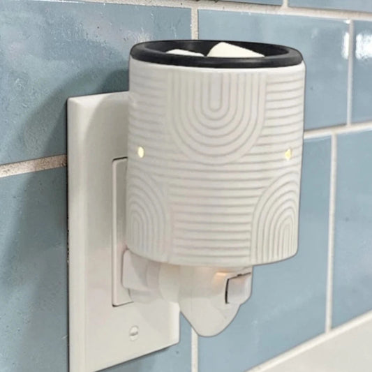 Art Deco candle wax warmer plugged into an outlet on the wall.