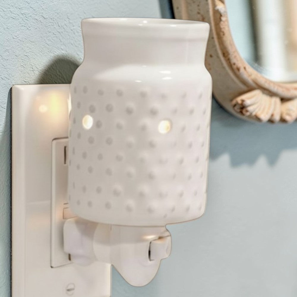 White candle wax warmer plugged in a bathroom setting.